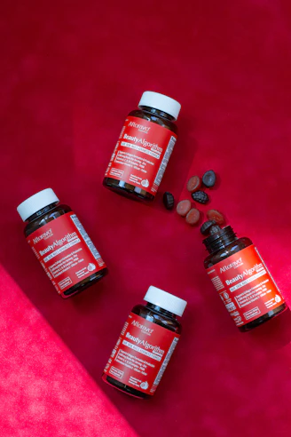 Three bottles of vitamins sitting on a pink surface