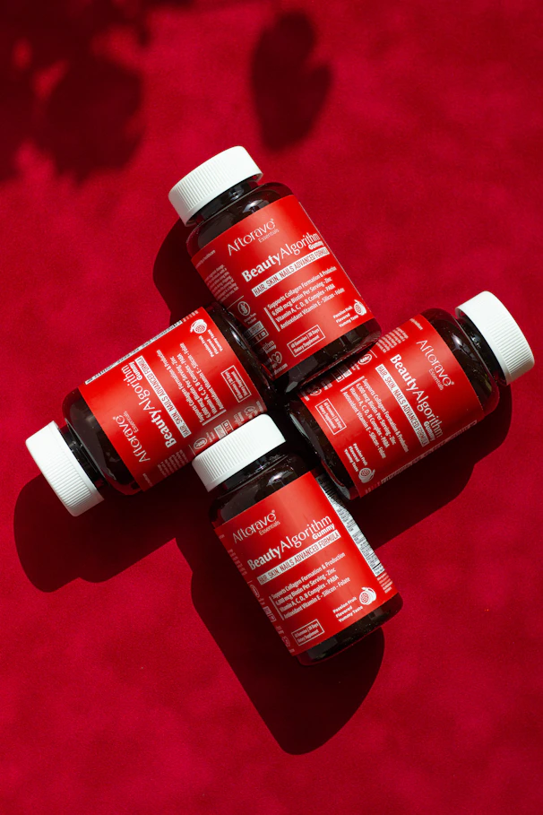 Three bottles of red liquid sitting on top of a red surface