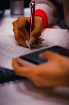 A person writing on a piece of paper with a pen
