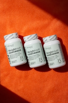 Three bottles of pills sitting on top of an orange blanket
