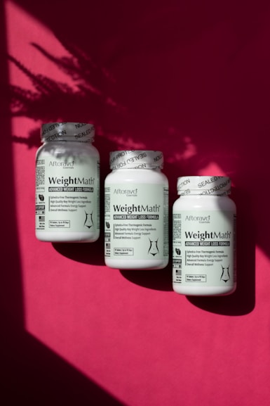 Three jars of weight loss pills on a pink background
