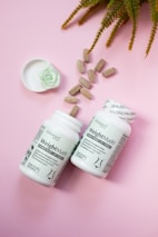 Two bottles of vitamin supplements next to a plant