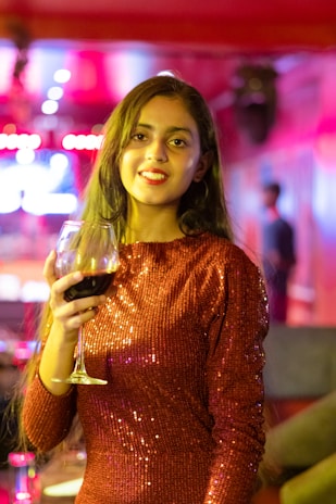 A woman in a red dress holding a glass of wine
