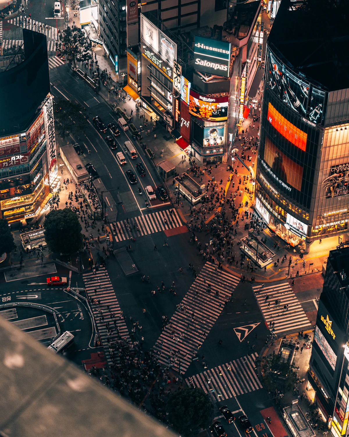 Shibuya Scramble crossing from above, lit by neon billboards at night
