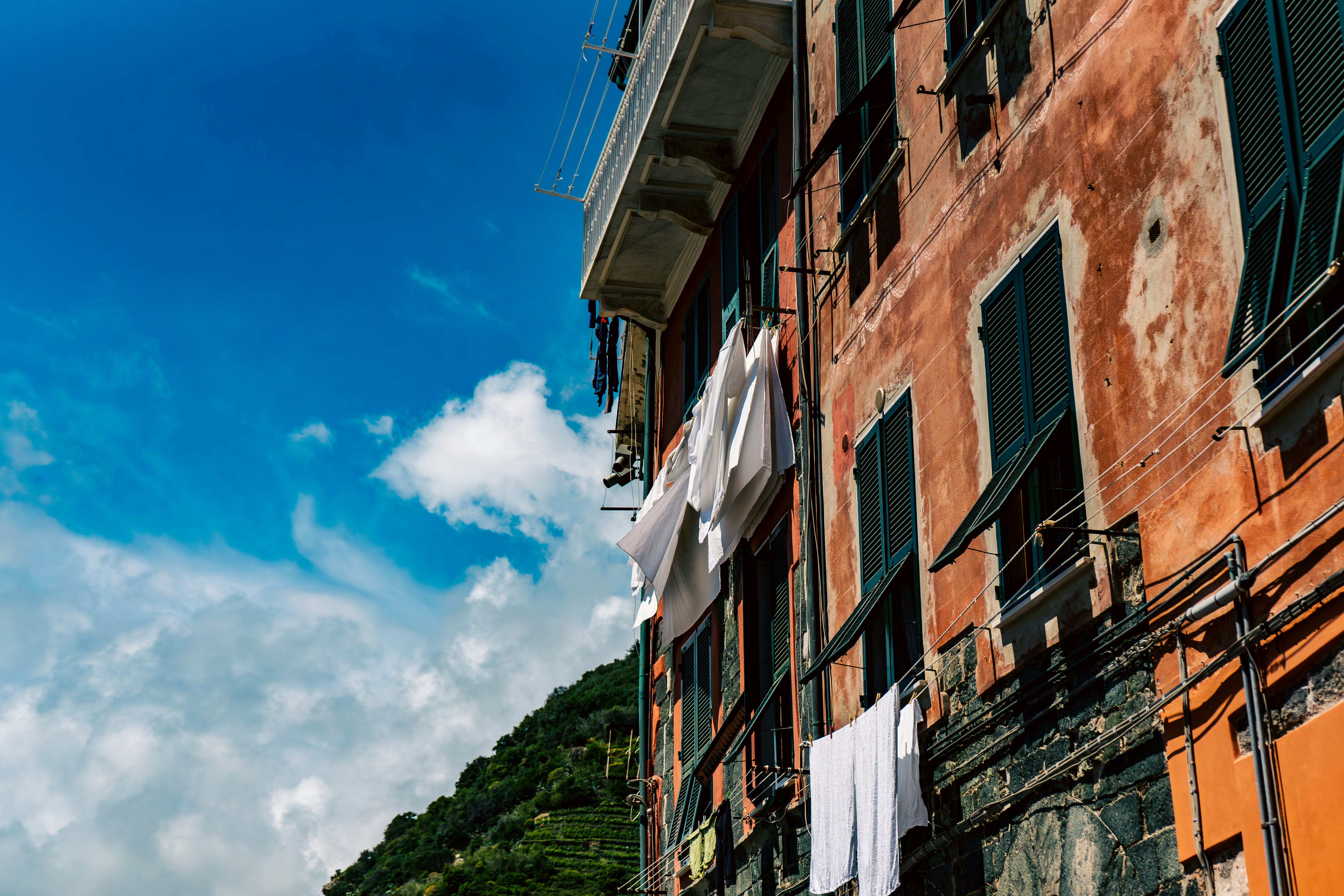 Narrow alley with rustic buildings and hanging laundry in Cinque Terre, Italy, showcasing local Italian charm