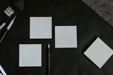 A black table topped with white cards and a pencil