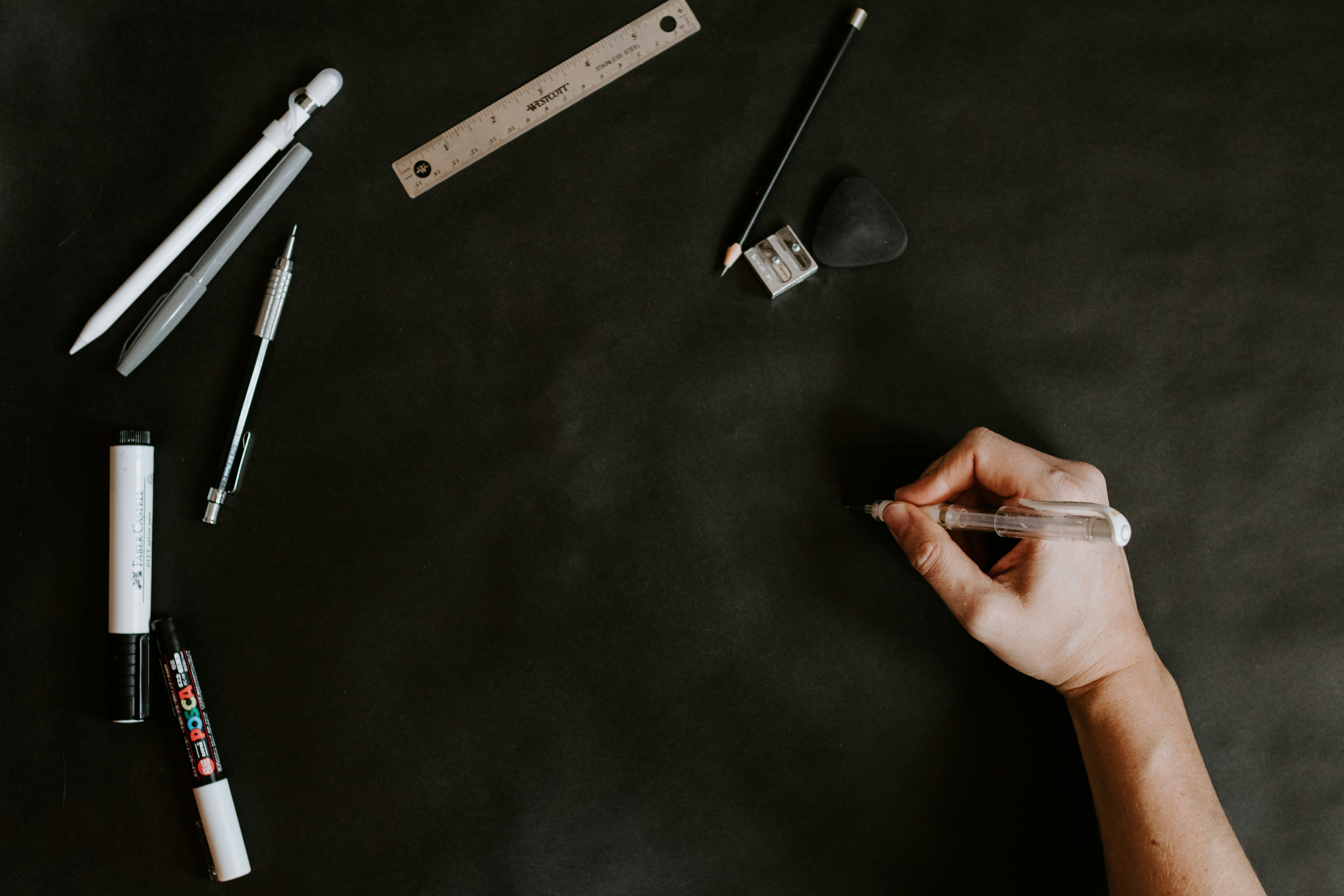 A person writing on a blackboard with pens and markers
