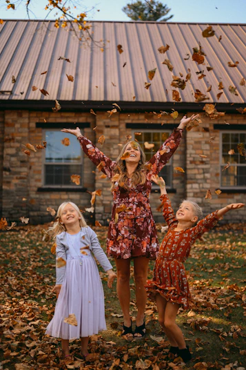 Three young girls are throwing leaves in the air