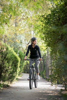 A woman riding a bike down a tree lined path