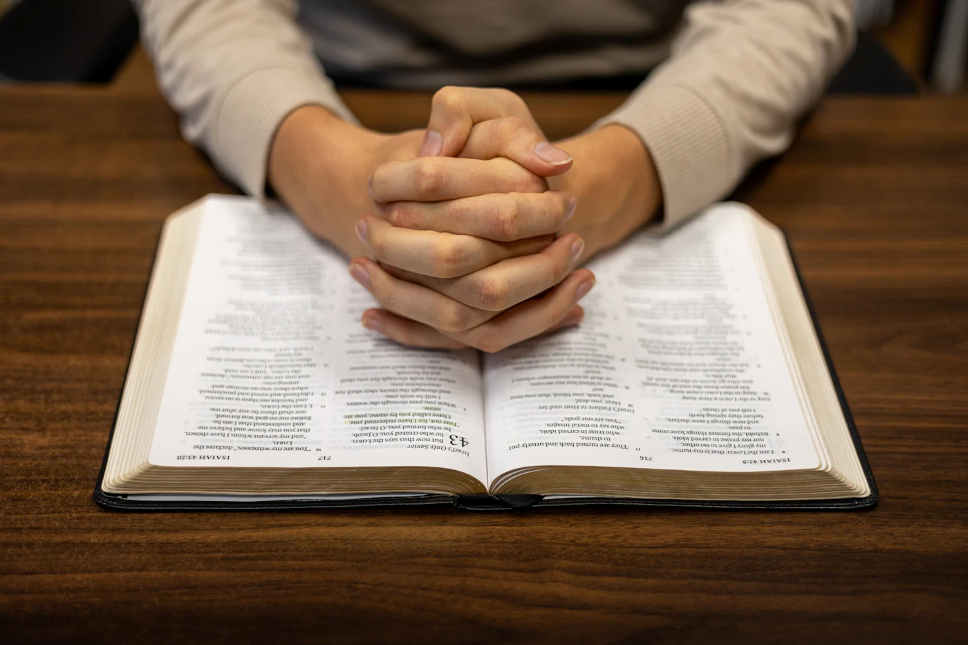 Unas manos cruzadas sobre una Biblia abierta