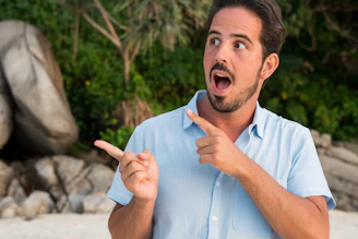A man pointing at something while standing on a beach