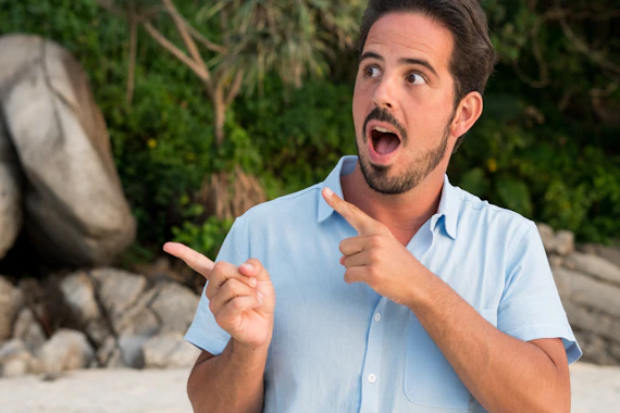 A man pointing at something while standing on a beach