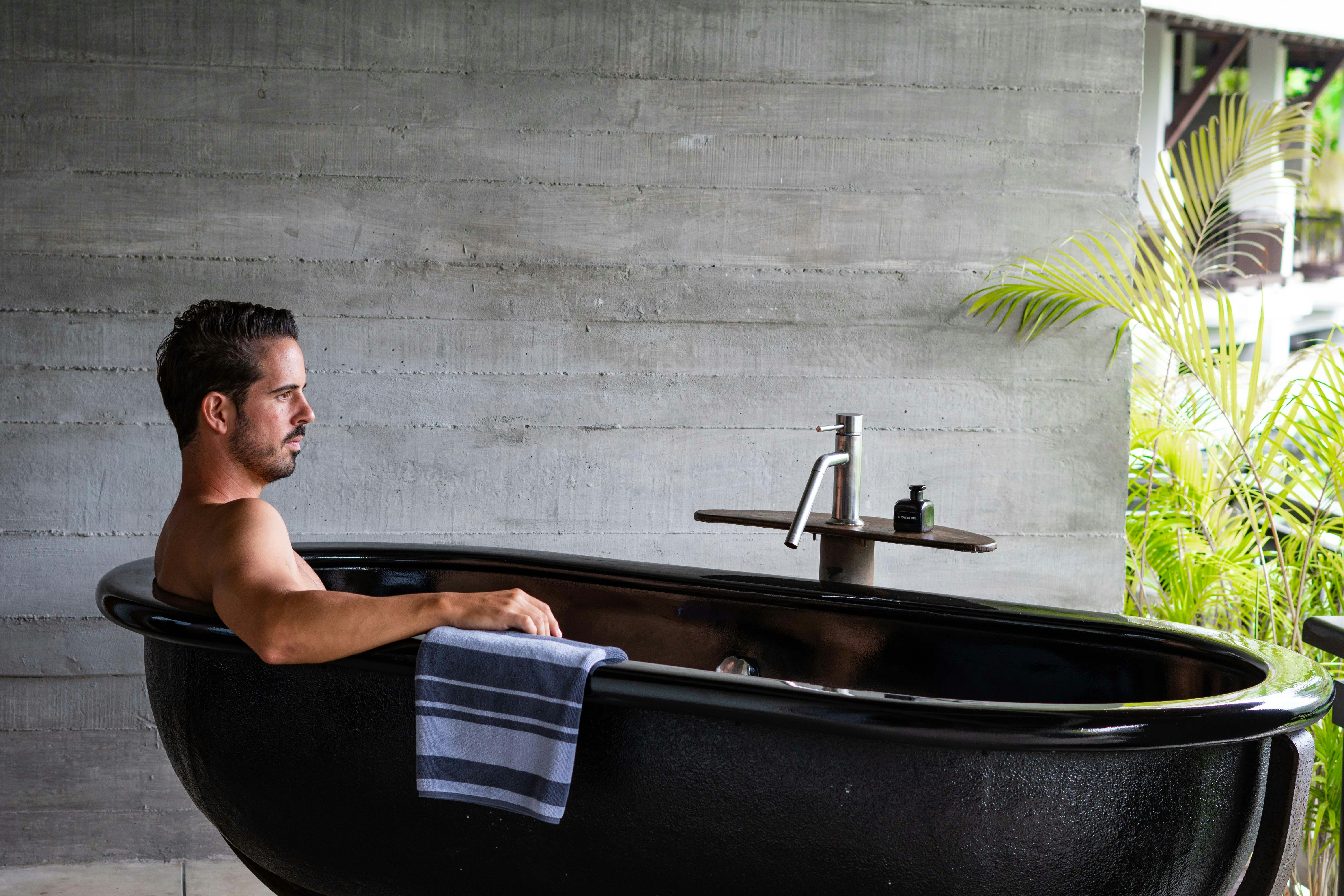 A man sitting in a black bath tub