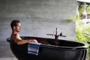 A man sitting in a black bath tub