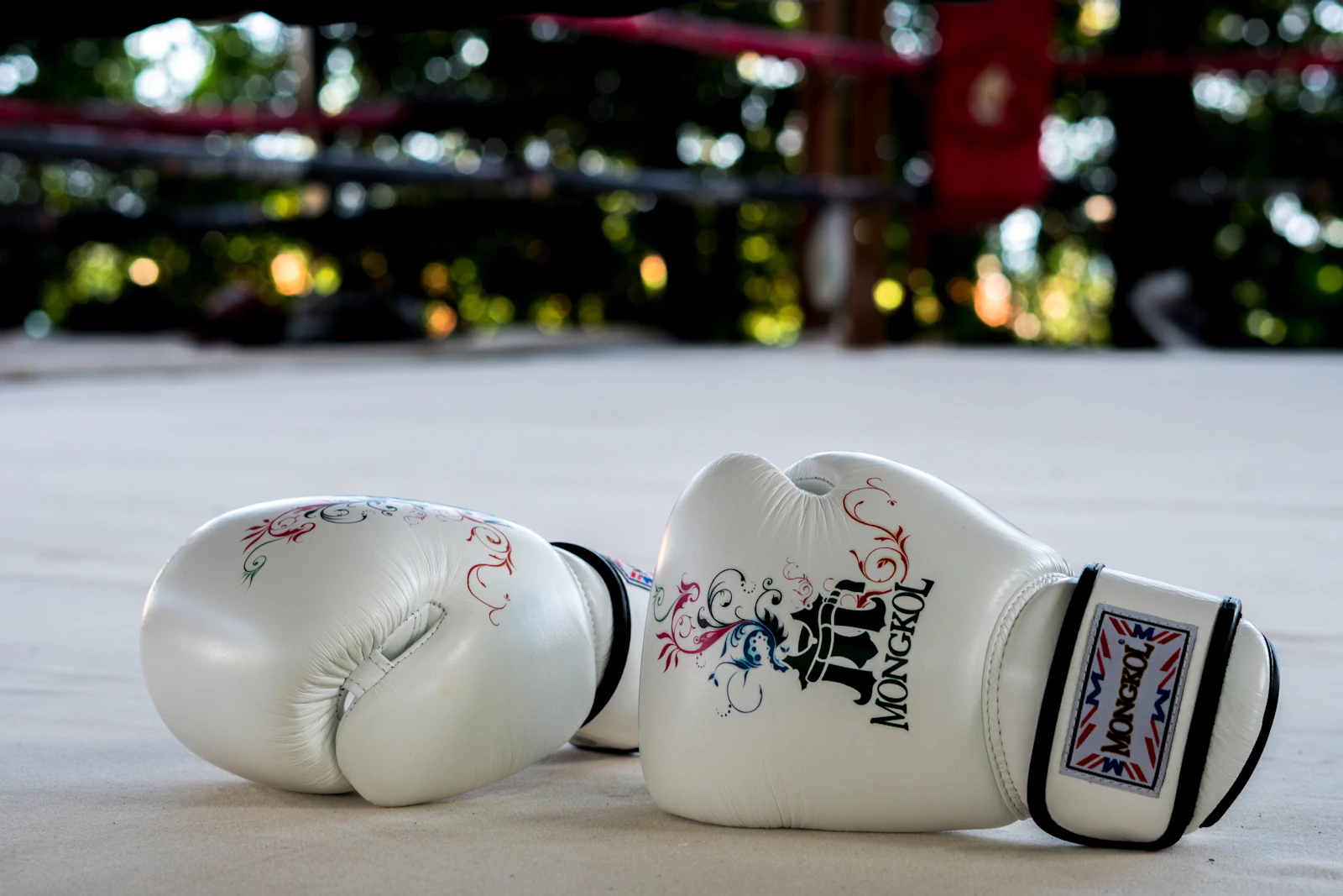 A pair of white boxing gloves resting on the floor after training