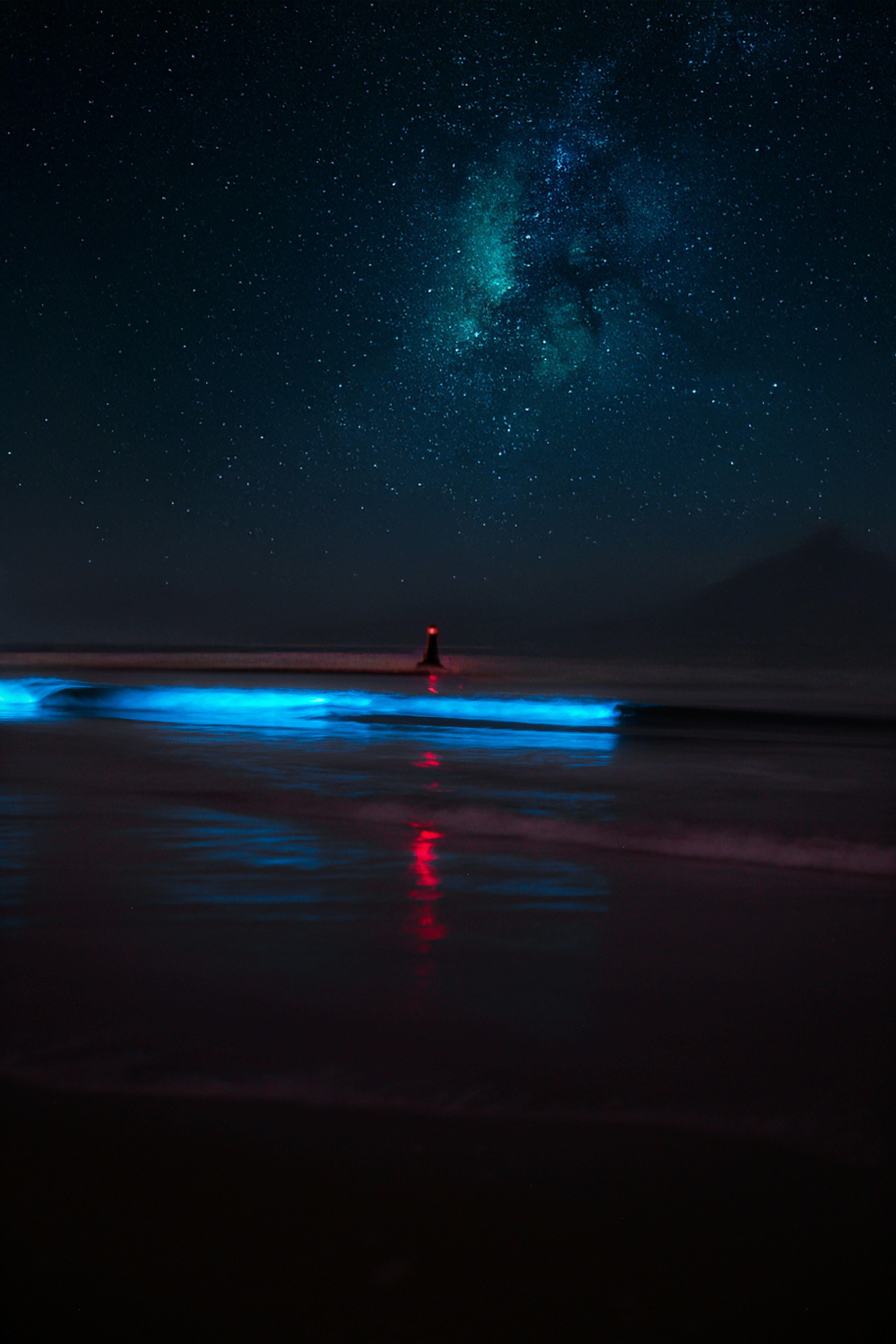 A person standing on a beach under a night sky