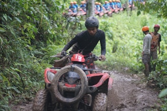 A man riding on the back of a red four wheeler