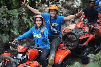 A man and a woman riding four wheelers in the jungle