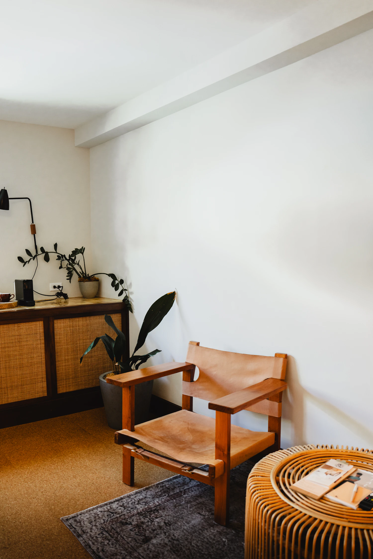 Wooden chair, cane cabinet, wooden table and indoor plant in a warm minimal interior