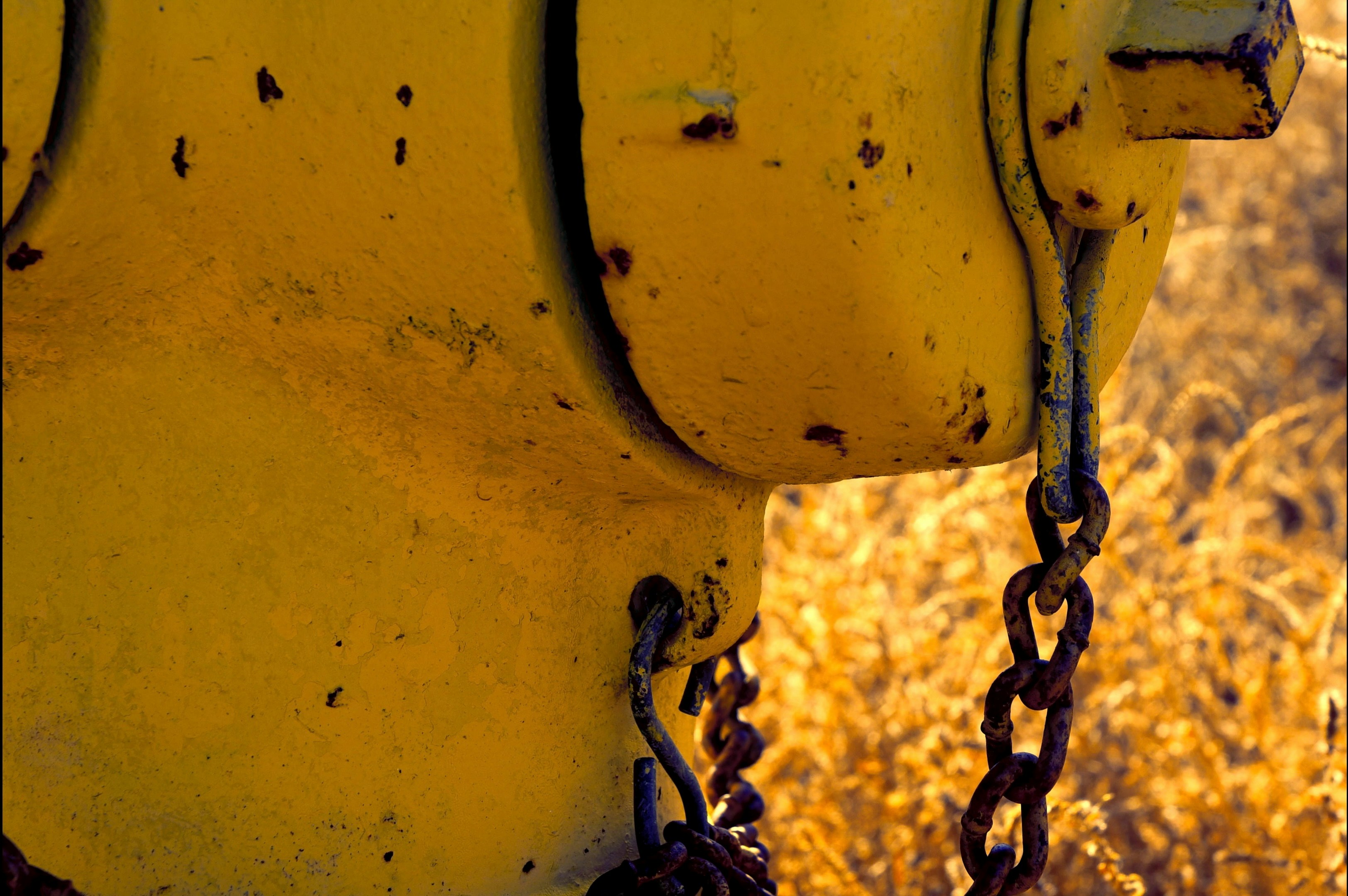 A yellow fire hydrant with chains hanging from it