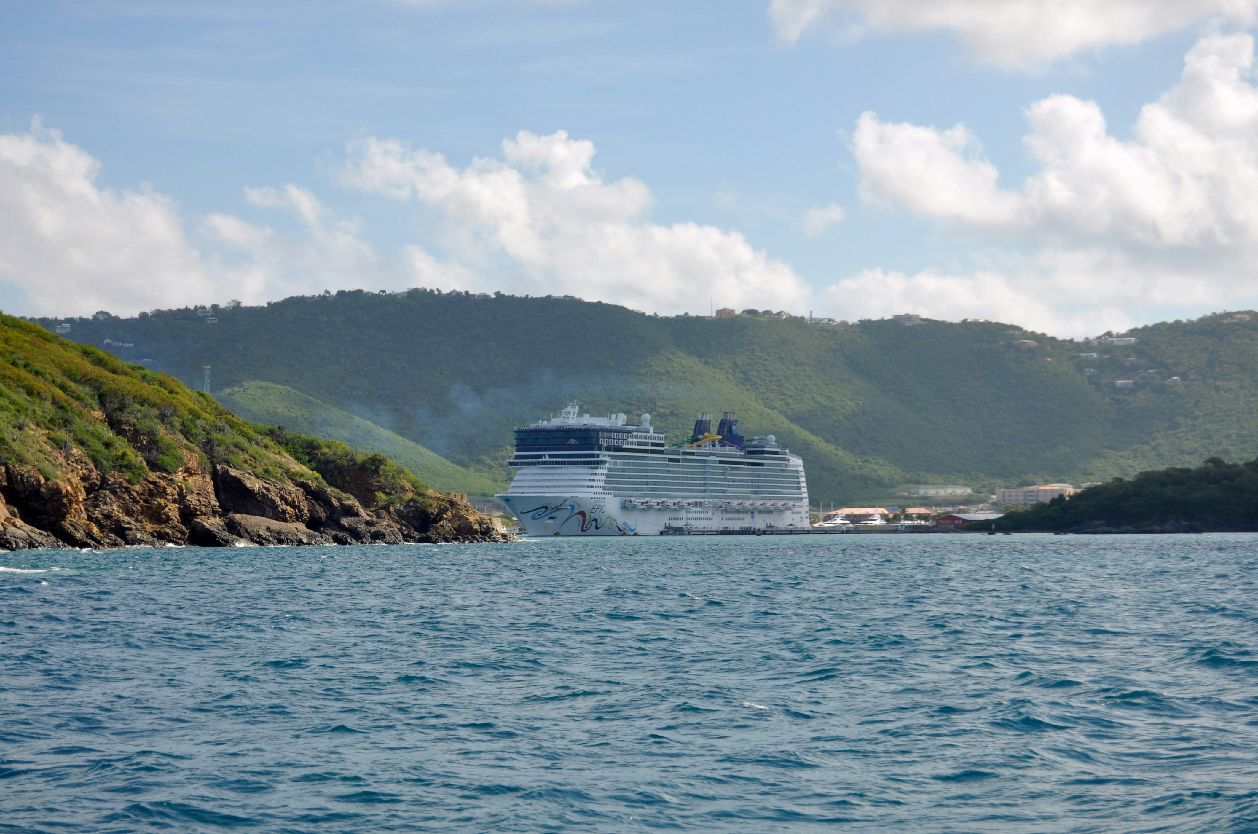 A cruise ship in the water near a rocky shore