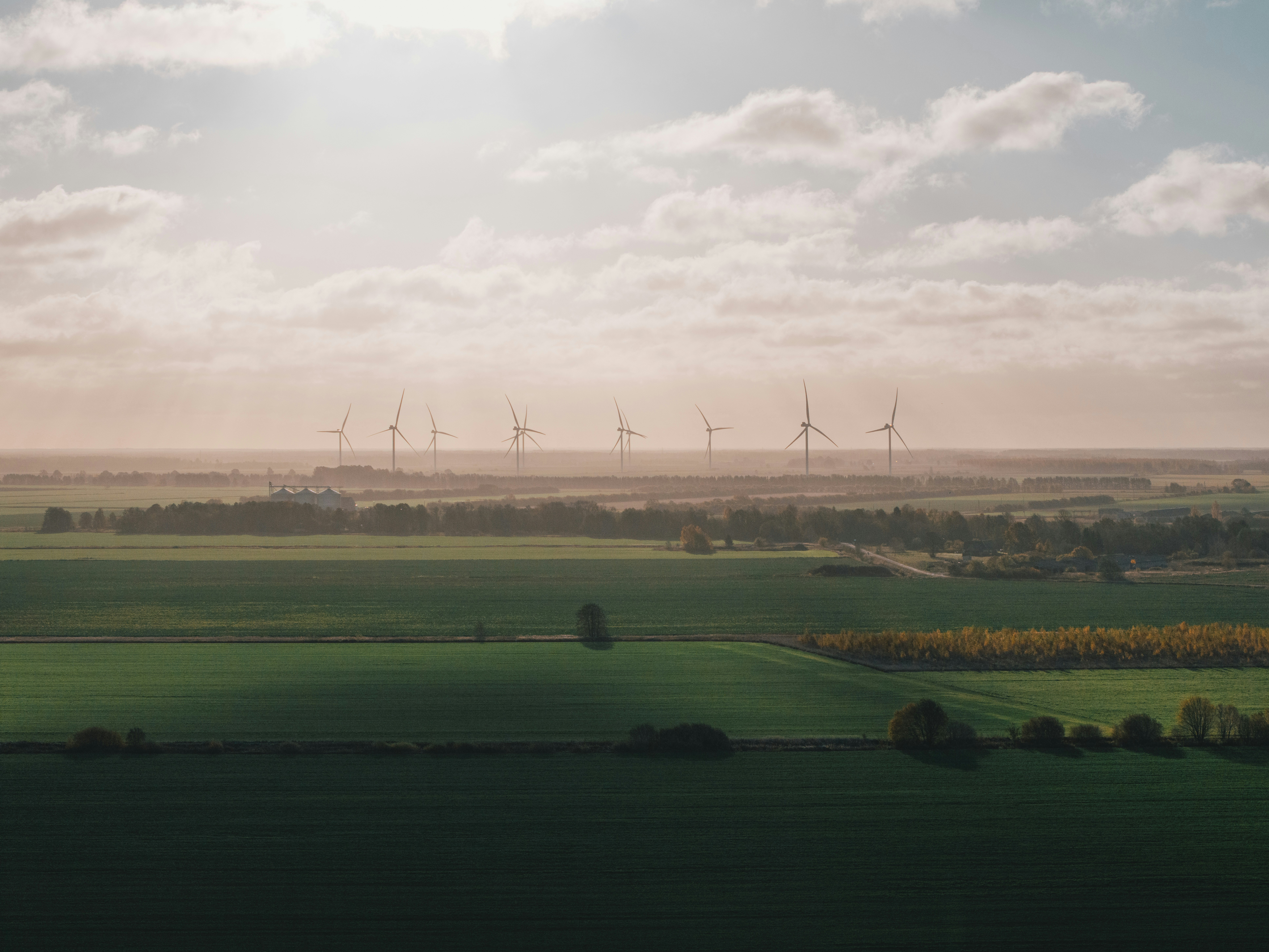 A view of a green field with windmills in the distance