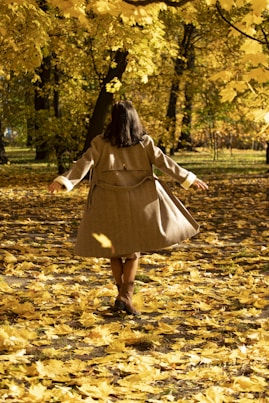 A woman walking through a leaf covered park