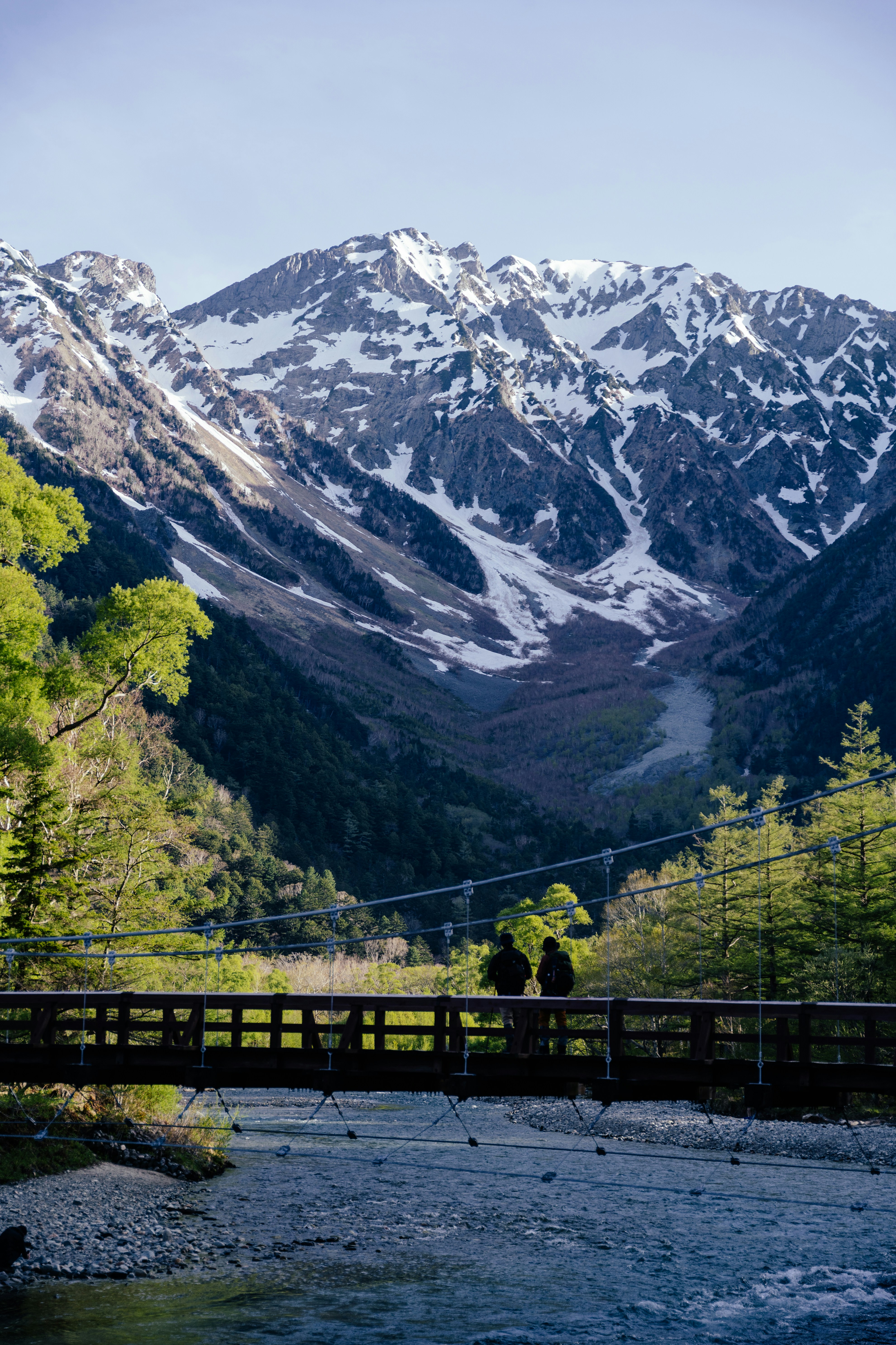 A bridge over a river in front of a mountain range