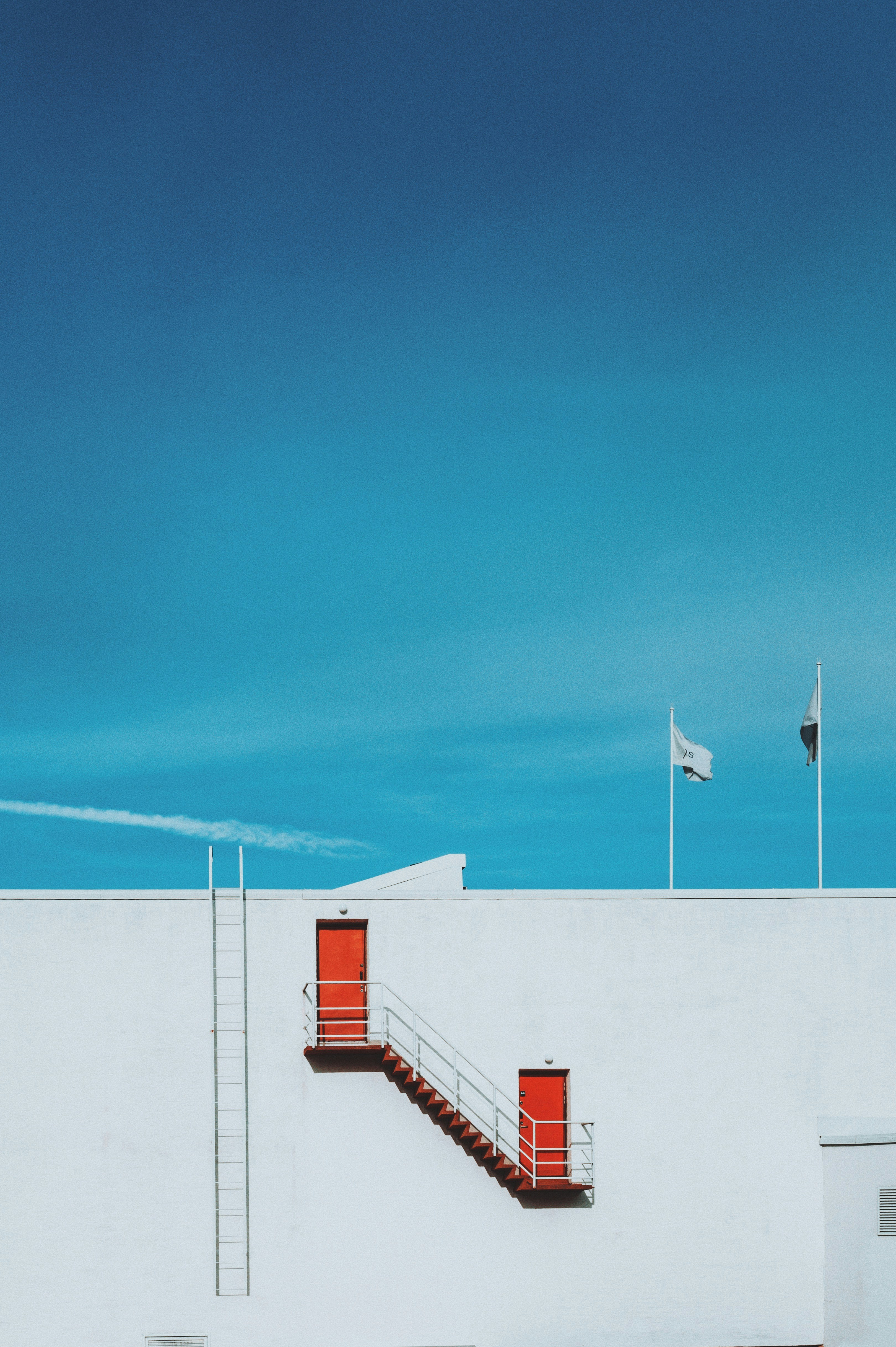 白い建物に赤いドアと階段