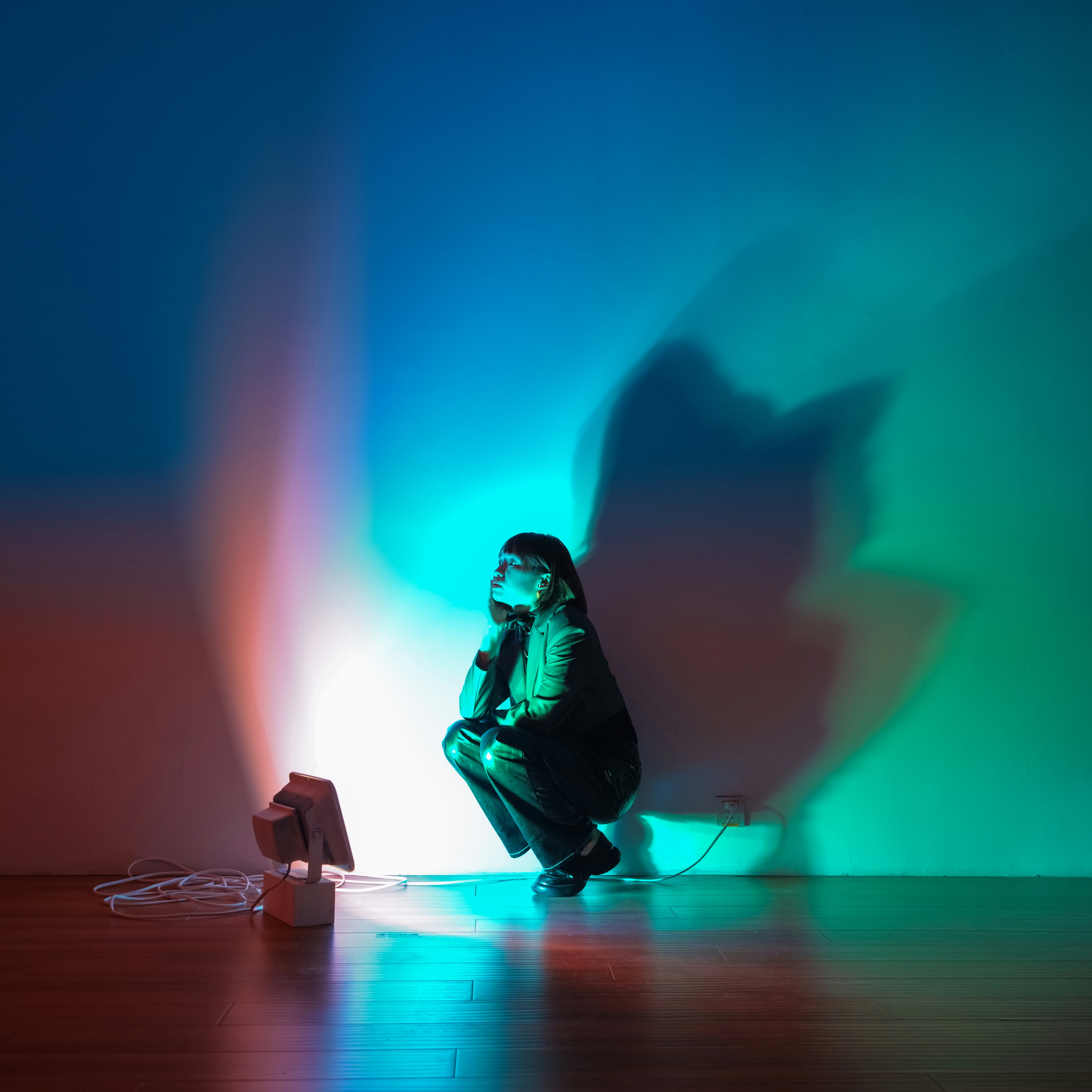 A person sitting on a floor in front of a wall