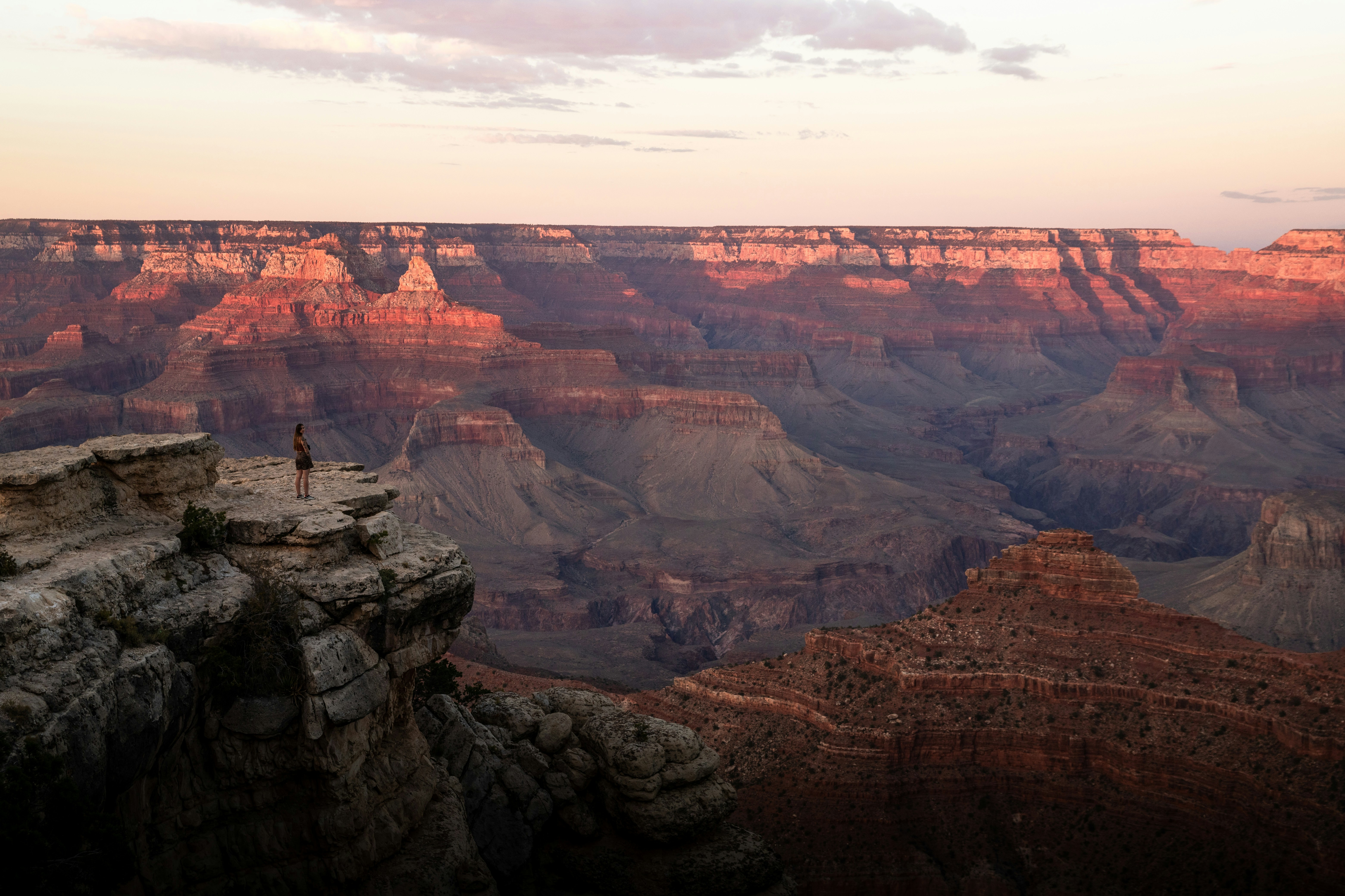 A man standing on the edge of a cliff at sunset