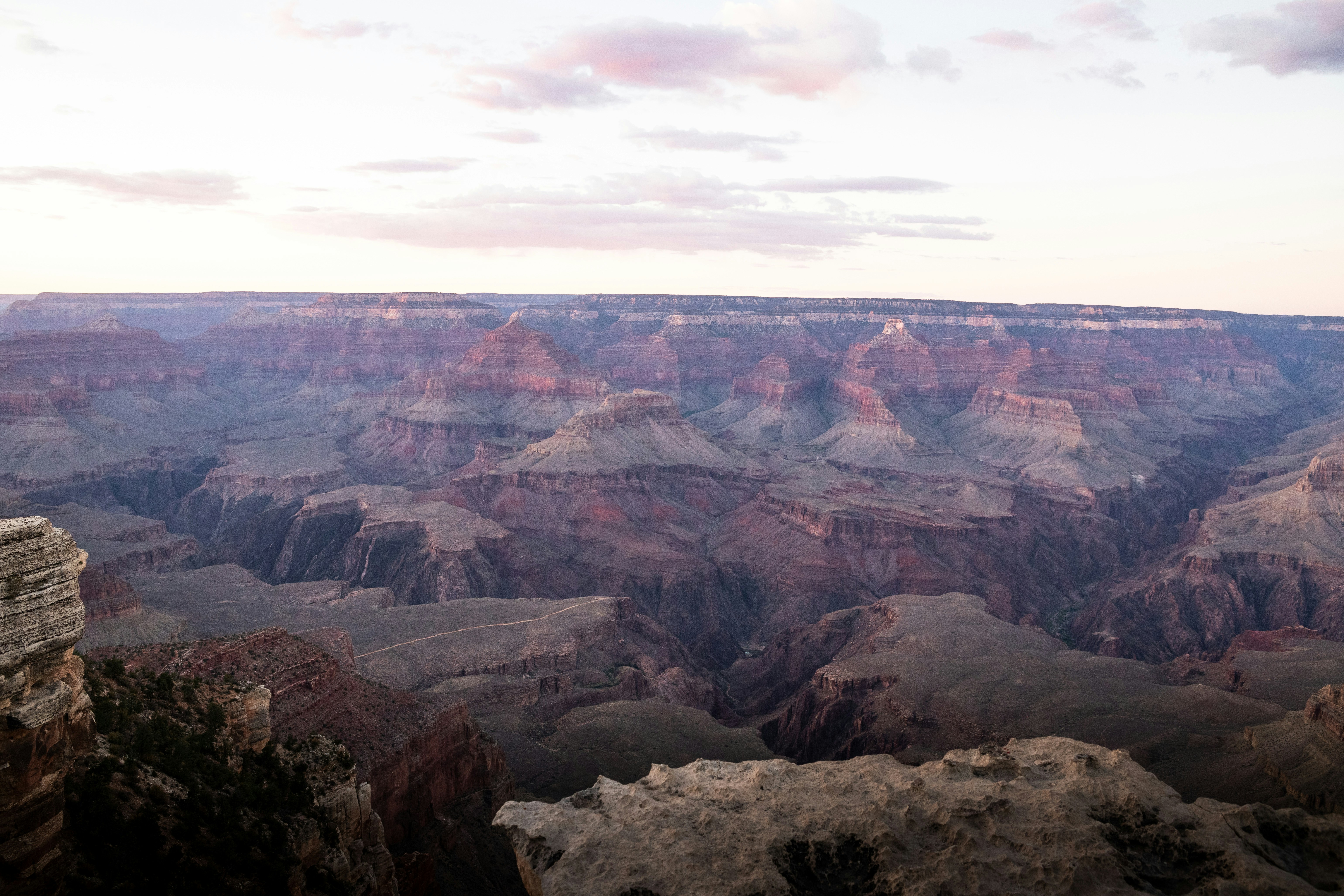 A man standing on a ledge at the edge of a cliff