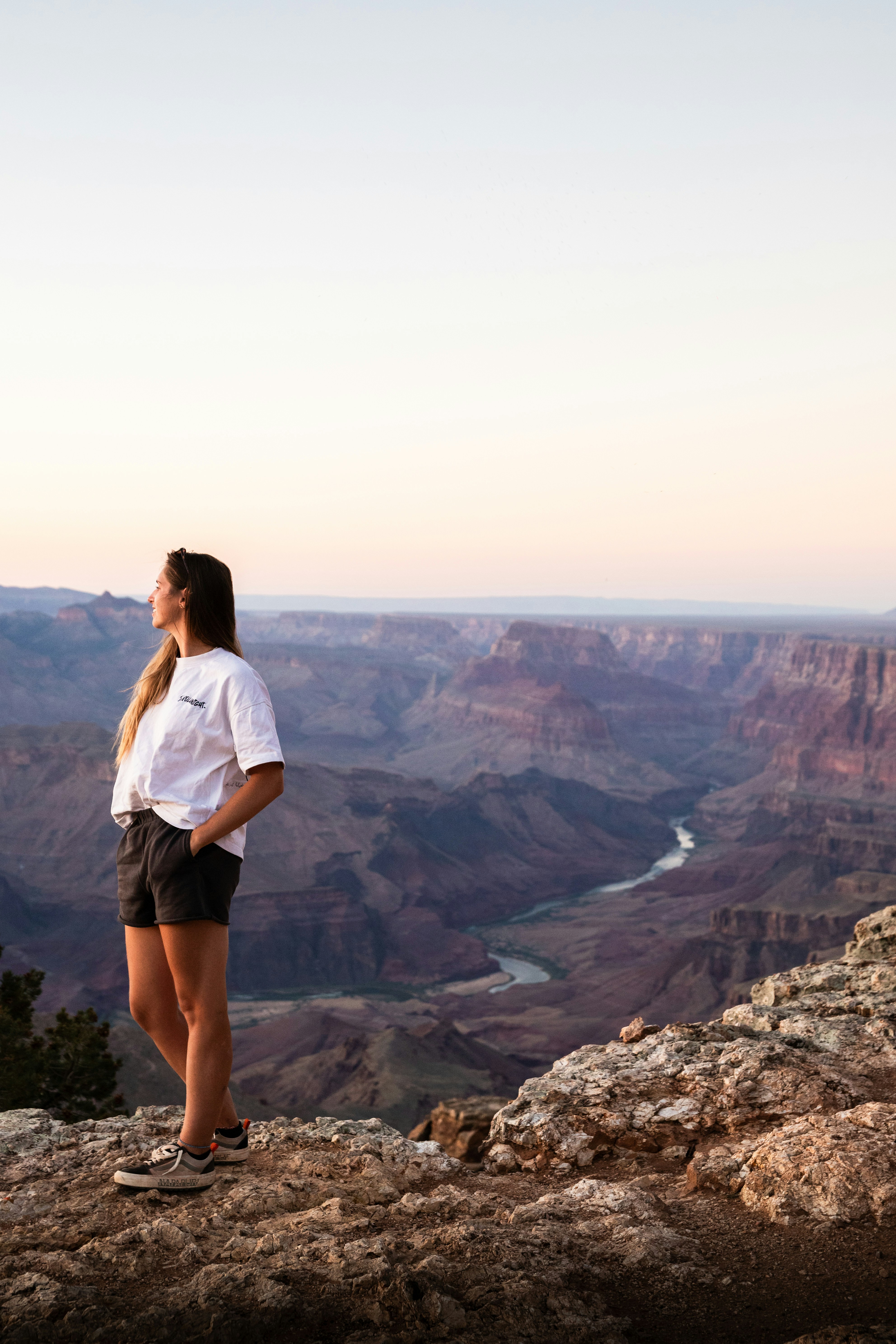 A woman standing on top of a cliff next to a river