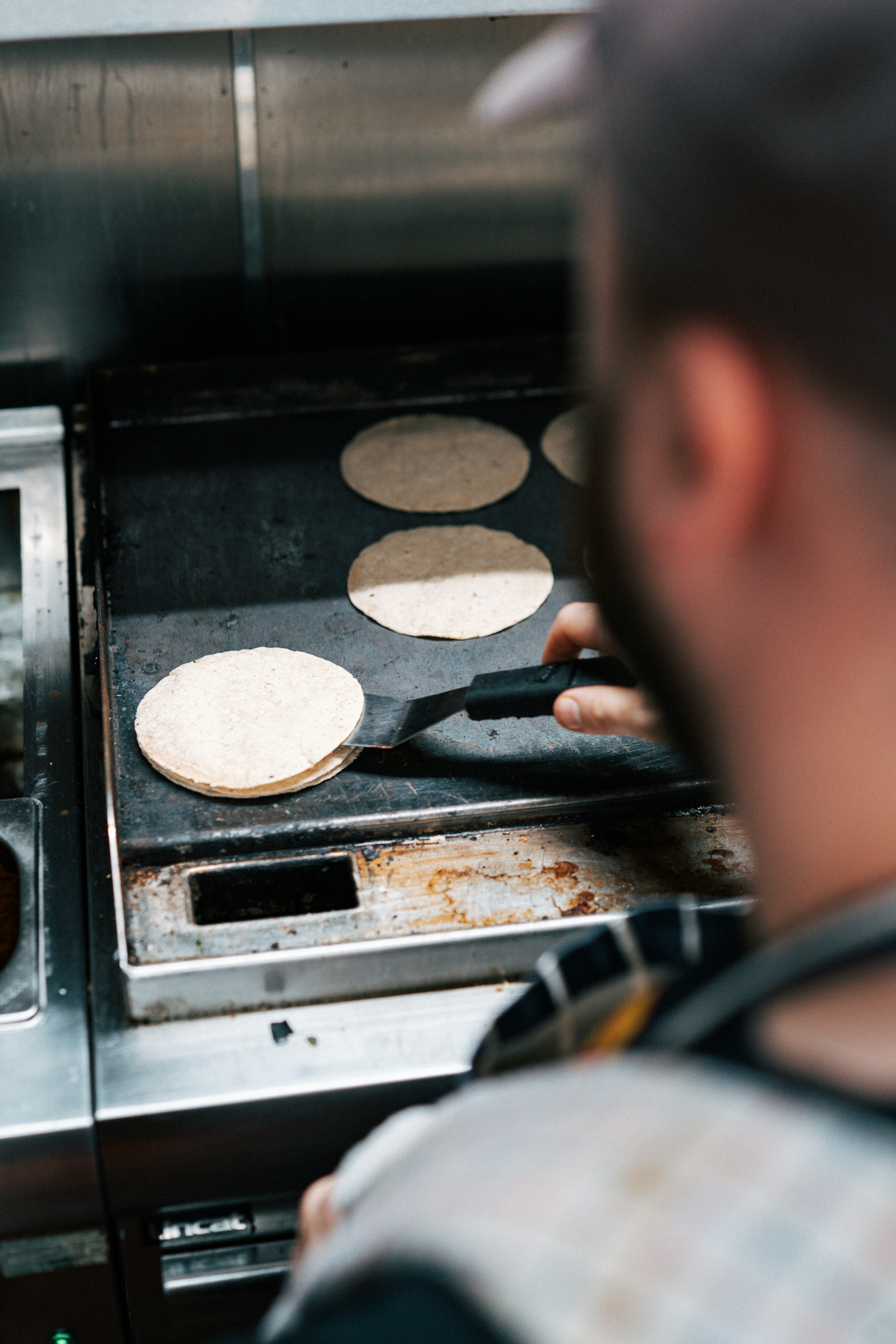 A man in a kitchen cooking food on a grill