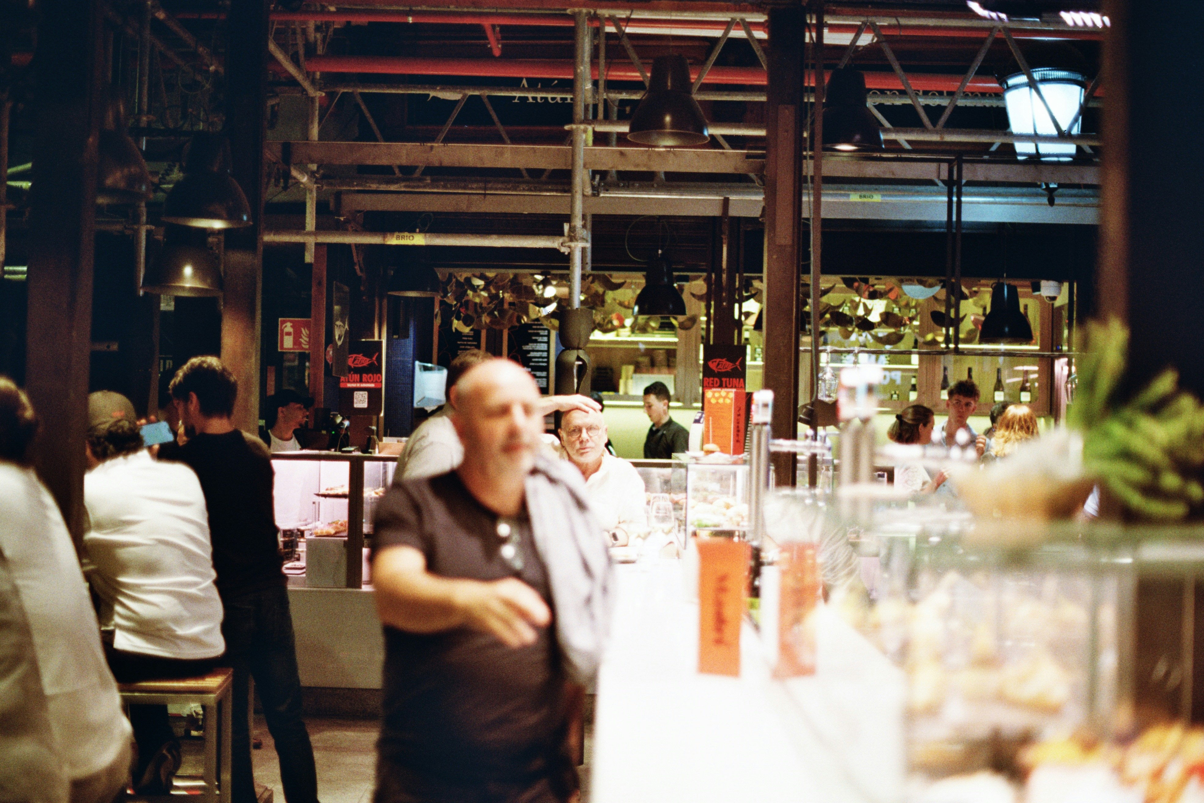 A group of people standing around a bar, 