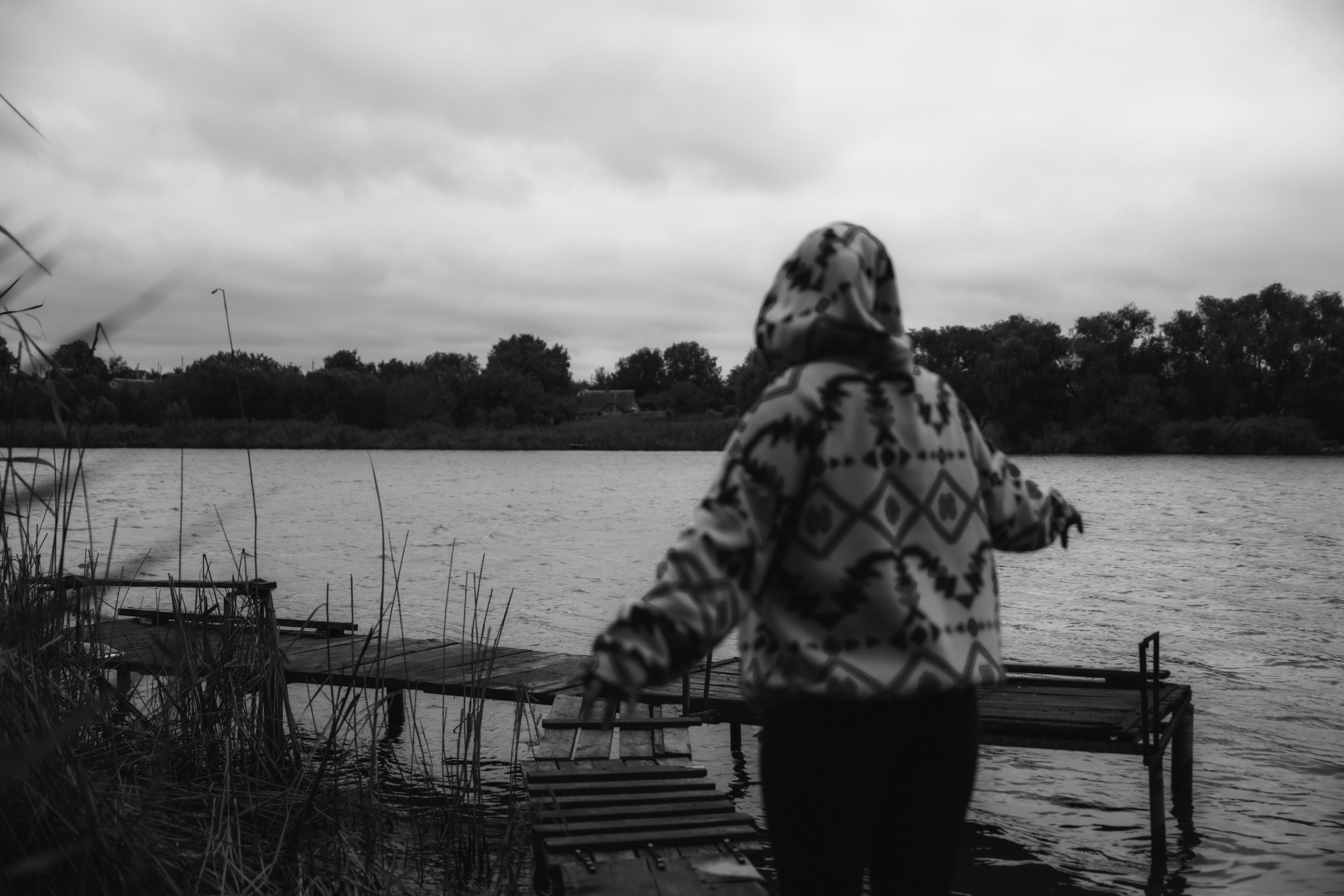 A person standing on a dock next to a body of water