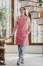 A woman in a pink apron standing in front of a staircase