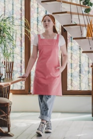 A woman in a pink apron standing in front of a staircase