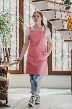 A woman in a pink apron standing in front of a staircase