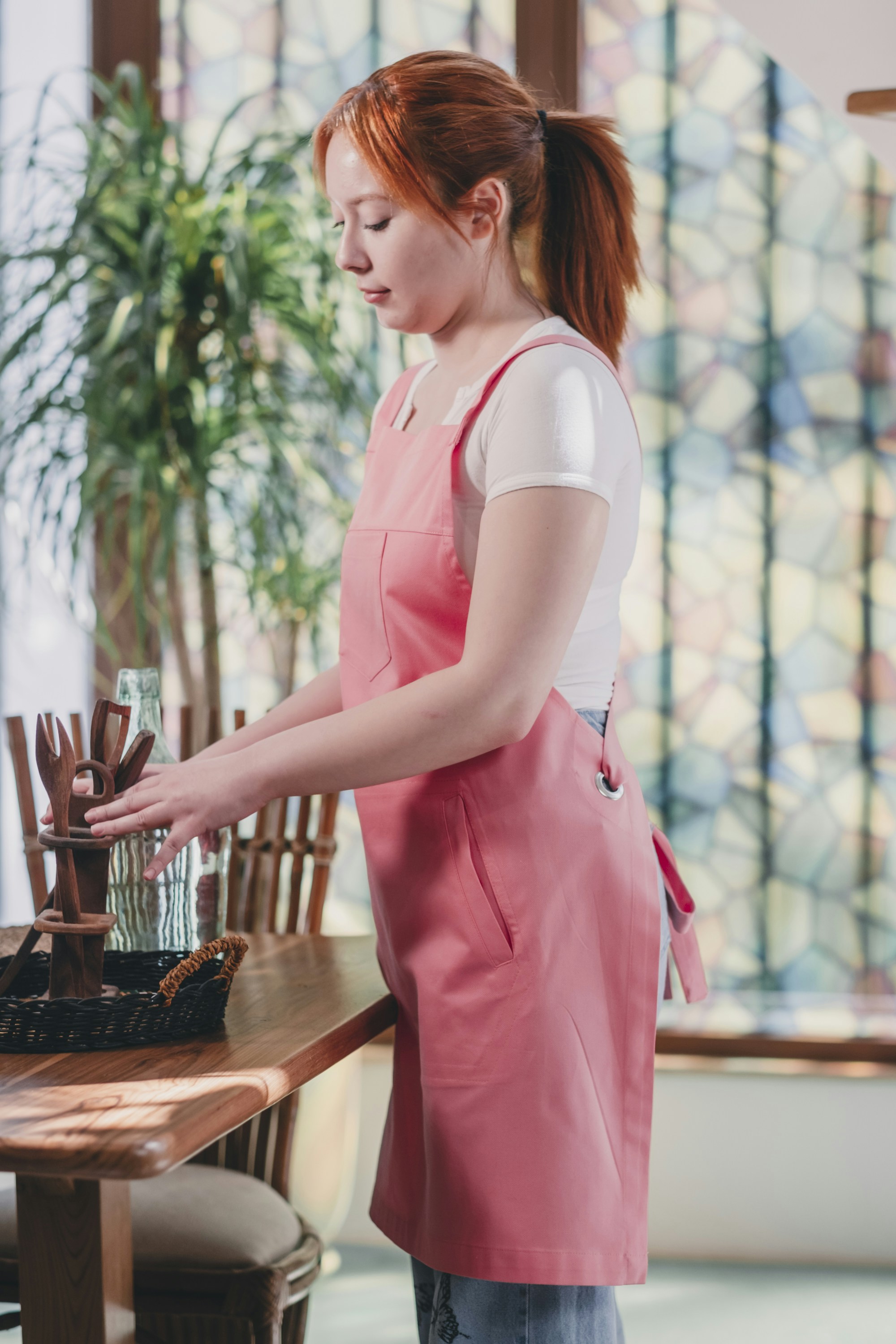 Eine Frau in einer rosa Schürze steht an einem Tisch