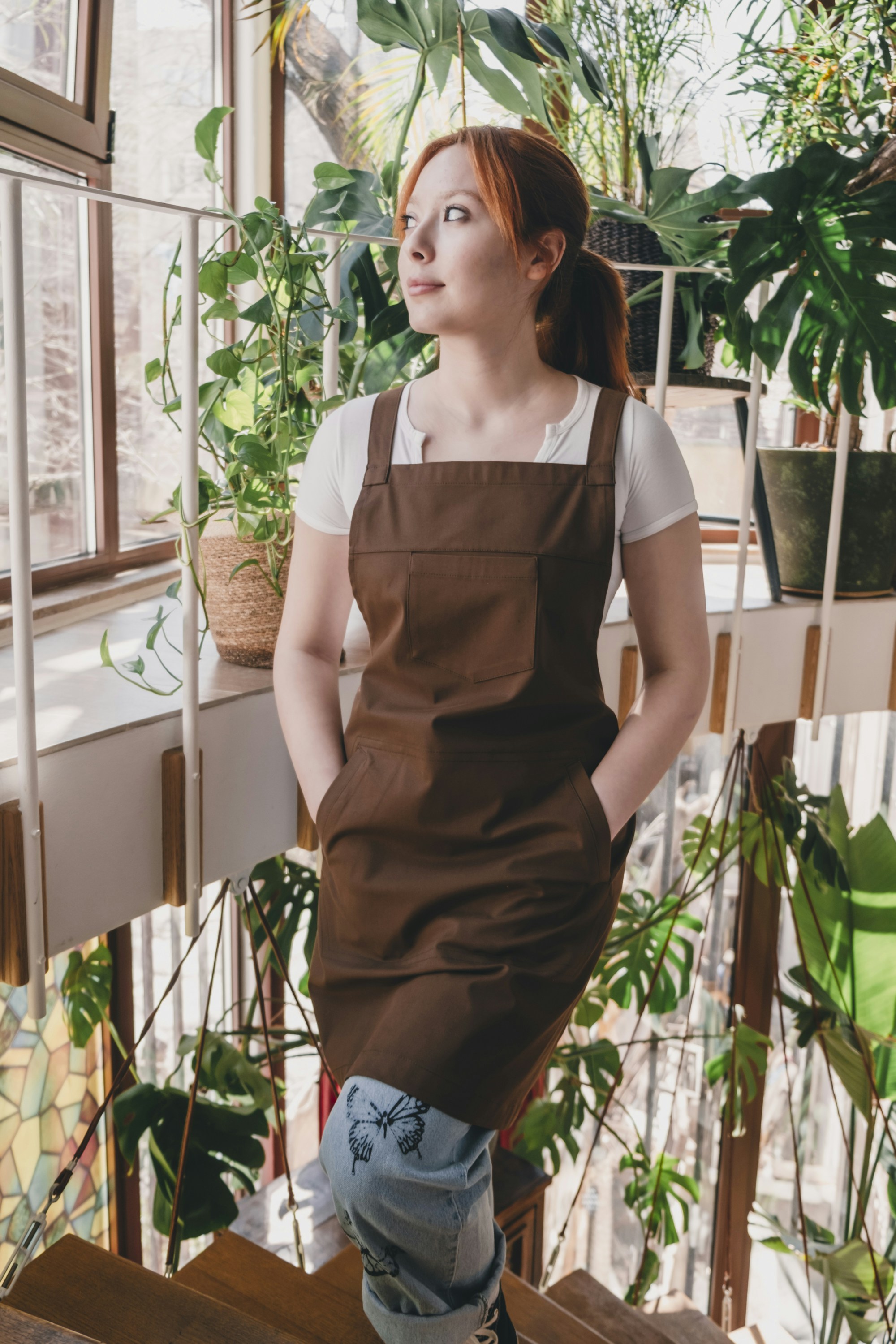 A woman in a brown apron standing on a stair case