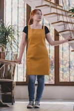 A woman in an orange apron standing in front of a staircase