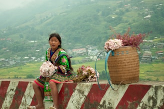A woman sitting on a wall with a basket of flowers