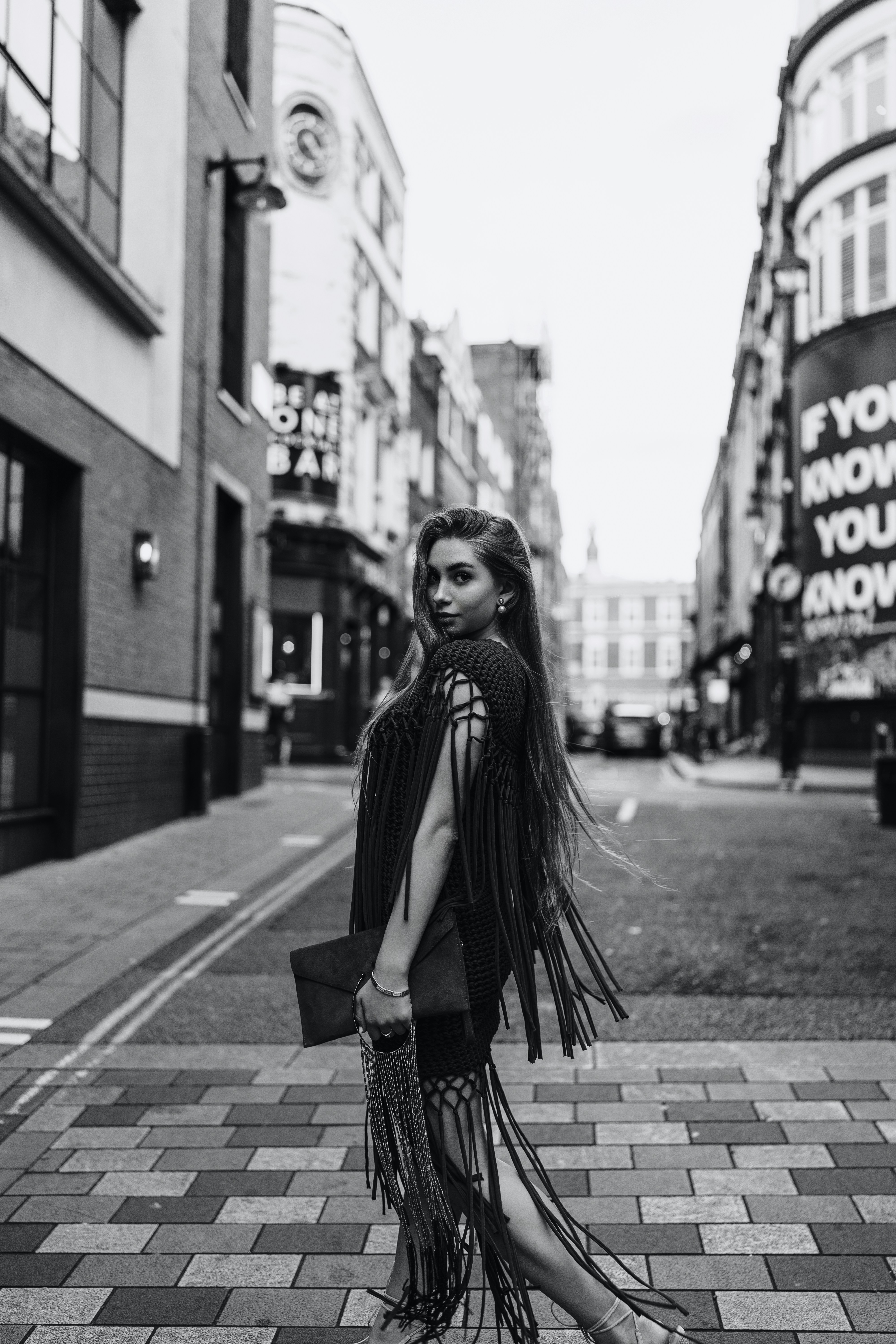 A woman standing on a sidewalk in front of a building