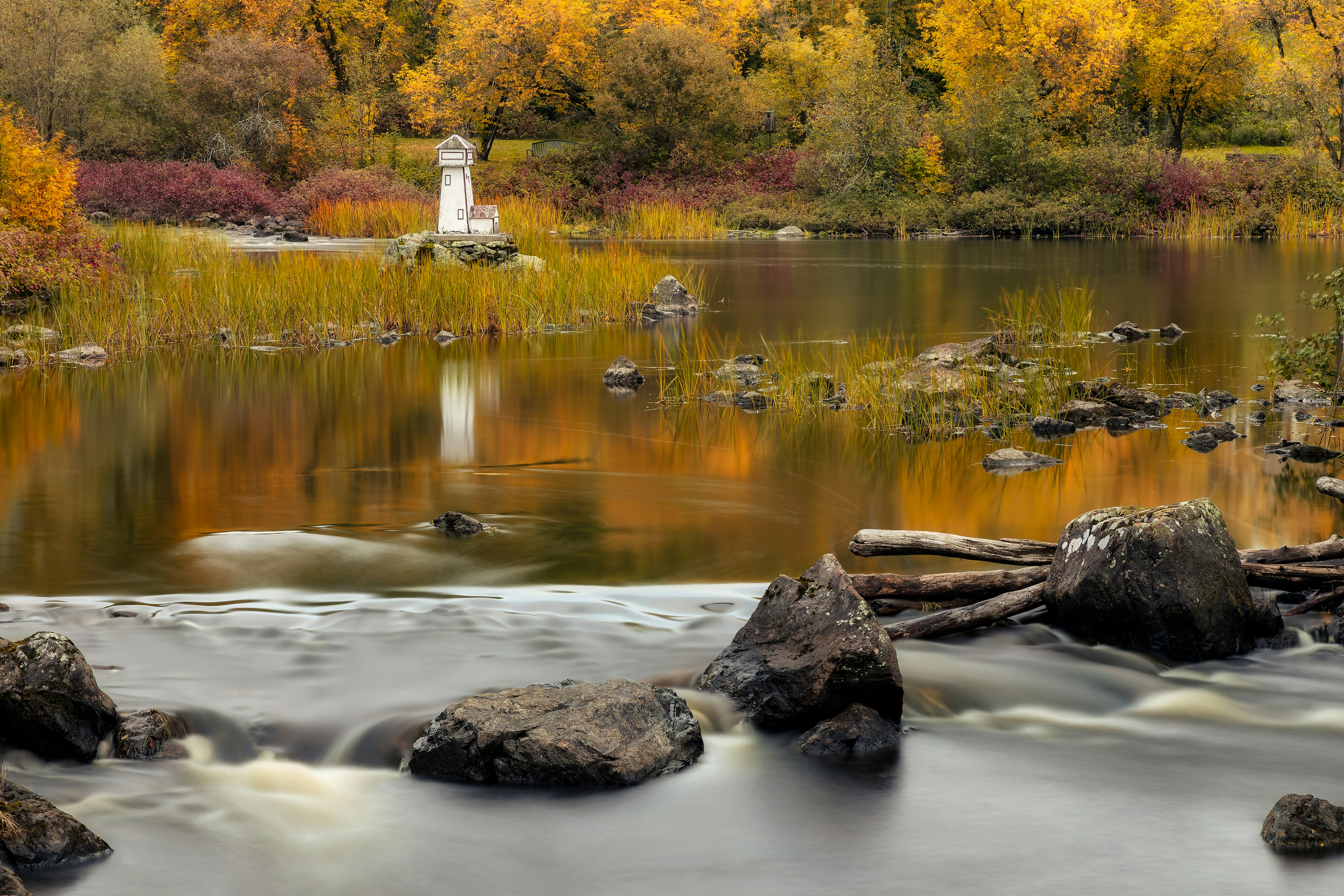 Une rivière avec des rochers et un phare en arrière-plan