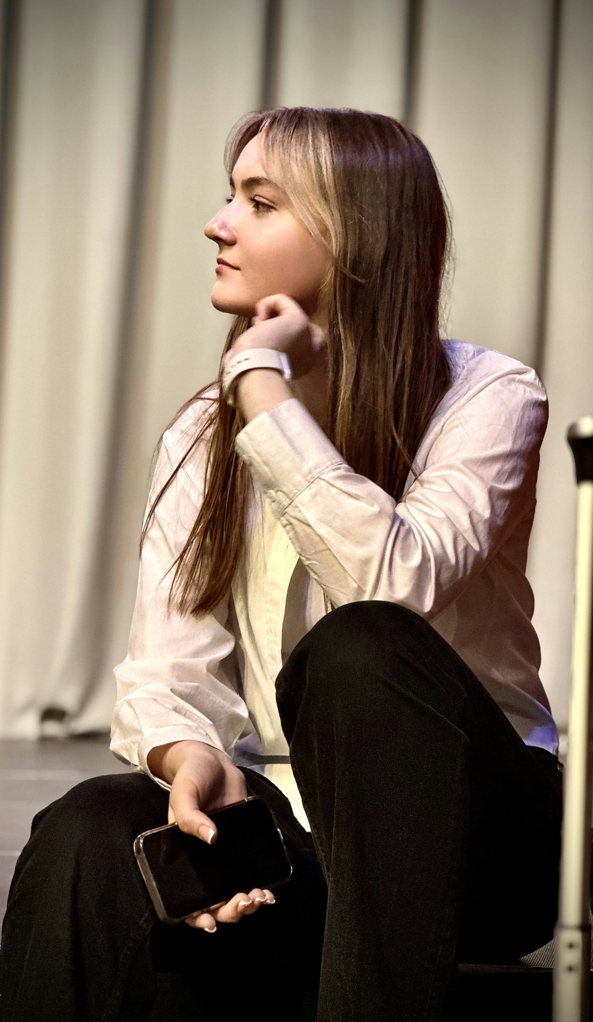 A woman sitting on a chair with a cell phone in her hand