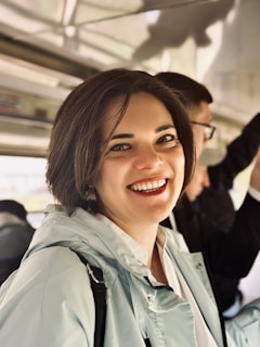 A woman is smiling while riding a bus