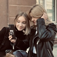 A couple of people that are looking at a cell phone