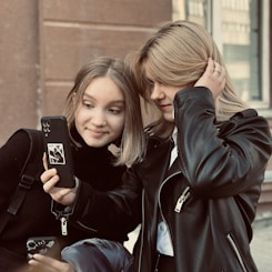 A couple of people that are looking at a cell phone