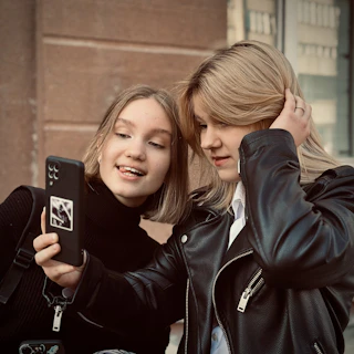 Two girls are looking at a cell phone